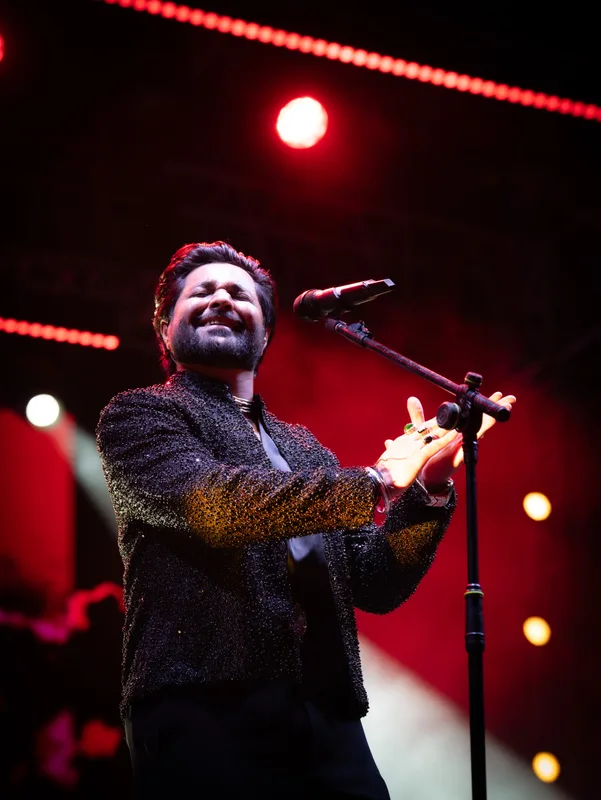 Singer smiling beside a microphone under red stage lights