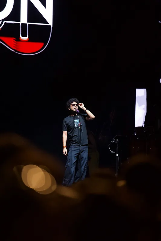 Singer in black performing on a dark stage above the audience