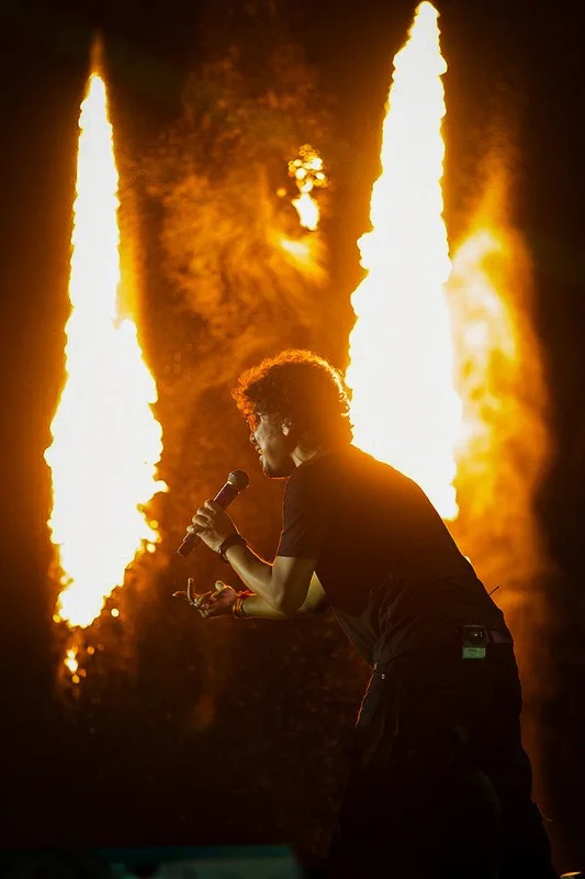 Singer holding a microphone between two columns of stage fire
